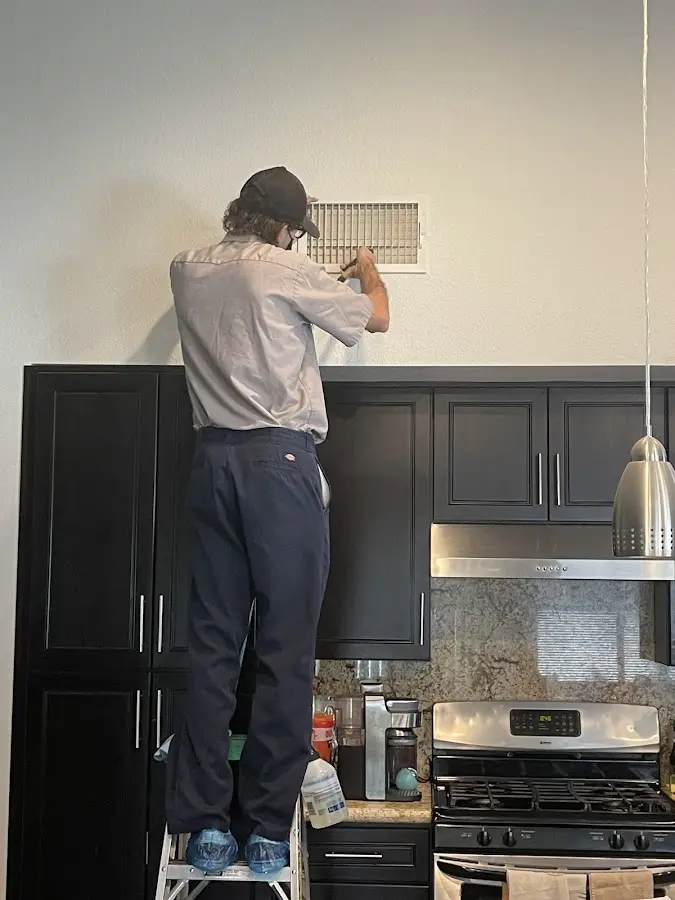 Technician inspecting an air vent during HVAC service in South Park